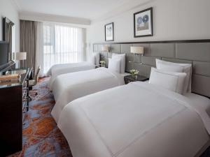 a hotel room with three beds and a television at Swissotel Makkah in Makkah