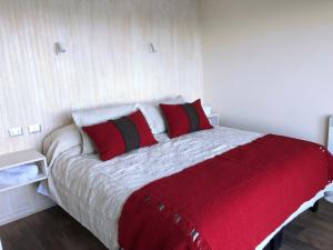 1 dormitorio con 1 cama con almohadas rojas y blancas en ApartHotel Kintumay, en Puerto Varas