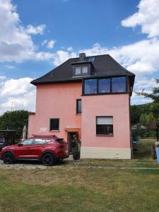 una macchina rossa parcheggiata di fronte a una casa di Achims Hüttl a Bad Berka