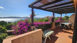 a patio with purple flowers and a table with a view at LA TERRAZZA SUL MARE - panoramic cottage overlooking sea and Caprera island in a quiet residential area - 150 mt from the sea in La Maddalena