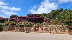 a stone retaining wall with a gate and flowers at LA TERRAZZA SUL MARE - panoramic cottage overlooking sea and Caprera island in a quiet residential area - 150 mt from the sea in La Maddalena