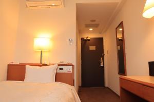 una camera d'albergo con letto, scrivania e porta di Aomori Green Park Hotel Annex ad Aomori