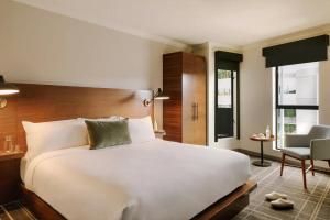 a bedroom with a large white bed and a chair at FOUND Hotel, Santa Monica in Los Angeles