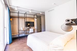 um quarto com uma grande cama branca e uma secretária em Ibis Roquebrune Cap Martin Menton em Menton