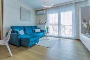 ein blaues Sofa im Wohnzimmer mit Fenster in der Unterkunft Apartament JP Jastrzębia in Jastrzębia Góra