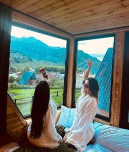 zwei Frauen, die auf einem Bett sitzen und aus dem Fenster schauen in der Unterkunft Hillside Kazbegi in Kazbegi