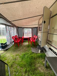 een groep rode stoelen en een tafel in een trailer bij Camping Alex in Cadenazzo