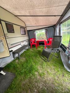 een camper met een tafel en stoelen in het gras bij Camping Alex in Cadenazzo