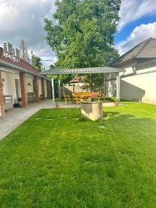 a yard with a picnic table and a pergola at Tündérkert Apartman in Gyula