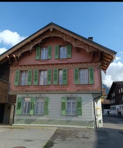 una casa de madera con persianas verdes en una calle en Mon Amour Apartment, en Interlaken