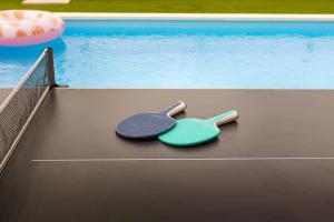 due racchette da ping pong sedute accanto a una piscina di Villa Aura a Pola (Pula)