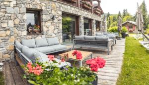 een patio met banken, een tafel en bloemen bij Les Chalets d'Adelphine & SPA in Les Gets