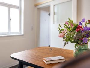 un vase de fleurs sur une table avec un livre dans l'établissement Ferienwohnung Brühler Hof, à Bad Berka