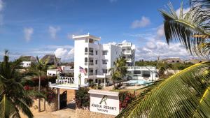 - un grand bâtiment blanc avec une piscine en face dans l'établissement Avana Resort Watamu, à Watamu