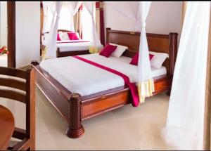 um quarto com uma cama de dossel e almofadas cor-de-rosa em Sienna Beach and Safaris Hotel em Entebbe