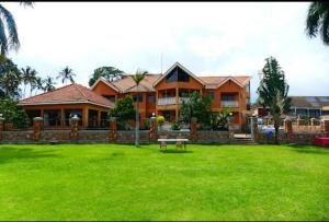 uma casa com um relvado verde em frente em Sienna Beach and Safaris Hotel em Entebbe