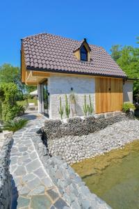 a house with a stone walkway next to a pond at Kompleksi Turistik DEA in Shkodër