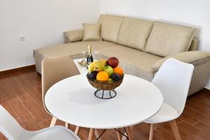 a bowl of fruit on a white table with a couch at KenDar Premium Apartments in Ulcinj