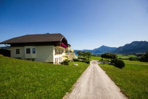 dom na trawiastym wzgórzu obok polnej drogi w obiekcie Gästehaus Stabauer w mieście Mondsee