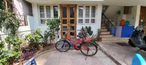 una bicicleta roja estacionada frente a una casa en Swanky Sojourns Cosy Home Stay, en Kolhapur