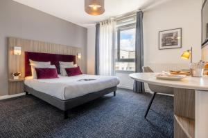 ナンシーにあるNemea Appart Hotel Grand Cœur Nancy Centreのベッドとテーブルが備わるホテルルームです。