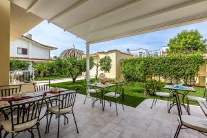 a patio with tables and chairs on a lawn at Casa Rita in Sabaudia