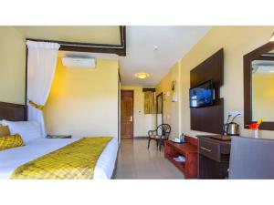 - une chambre avec un lit, un bureau et un miroir dans l'établissement Wigot Gardens Hotel, à Kisumu