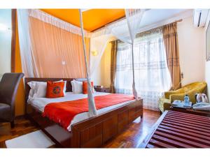 - une chambre avec un lit à baldaquin et une chaise dans l'établissement Wigot Gardens Hotel, à Kisumu