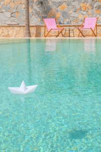 a paper boat in the water next to two chairs at Casa Selimi in Ulcinj