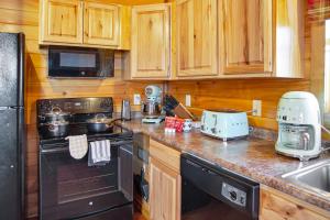 La cuisine est équipée de placards en bois et d'une cuisinière noire. dans l'établissement Cabin In The Smokeys, à Gatlinburg