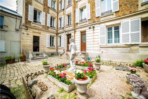 una estatua frente a un edificio con flores en Lovely Apartment Palace of Versailles, en Versalles