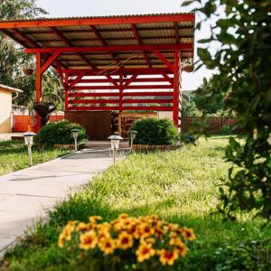 een rood paviljoen in een tuin met bloemen in het gras bij PICNIC Vendégház in Bogács