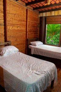 Habitación de madera con 2 camas y ventana en Cabaña Ave Del Paraiso, en Cartago