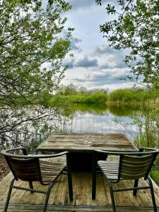 een tafel en twee stoelen op een steiger naast een meer bij Krusmølle Glamping in Aabenraa