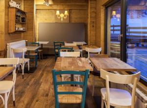 ein Restaurant mit Holztischen und -stühlen und einer Tafel in der Unterkunft Orso Bianco Hotel & Chalet in Sauze dʼOulx