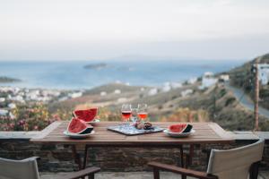 uma mesa de madeira com dois copos de vinho e melancia em Villa Il Paradiso Andros em Gavrio