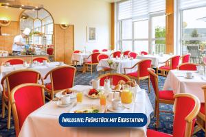 um restaurante com mesas brancas e cadeiras vermelhas em Best Western Ahorn Hotel Oberwiesenthal – Adults Only em Kurort Oberwiesenthal