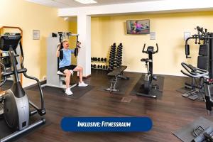 uma mulher num ginásio com pesos e equipamento de exercício em Best Western Ahorn Hotel Oberwiesenthal – Adults Only em Kurort Oberwiesenthal