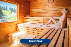 uma mulher sentada no interior de uma sauna em Best Western Ahorn Hotel Oberwiesenthal – Adults Only em Kurort Oberwiesenthal