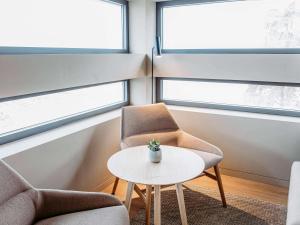 2 sillas y una mesa en una habitación con ventanas en Mercure Fátima, en Fátima