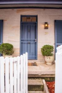 Balmain Sandstone Cottage في سيدني: بيت فيه باب ازرق وسياج ابيض