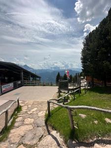 eine Bank im Gras in der Nähe eines Gebäudes mit Bergen in der Unterkunft Chalet da mont Resciesa in St. Ulrich in Gröden