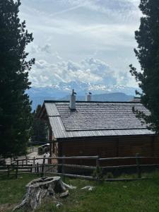 eine Scheune mit einem Zaun und Bergen im Hintergrund in der Unterkunft Chalet da mont Resciesa in St. Ulrich in Gröden