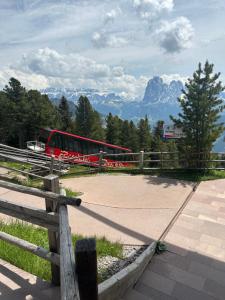 einem roten Bus, der neben einem Zaun mit einem Berg parkt in der Unterkunft Chalet da mont Resciesa in St. Ulrich in Gröden