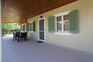 a porch of a house with green windows and a table at Olga Home Agios Ioannis Lefkada - Lefkada BnB in Lefkada Town