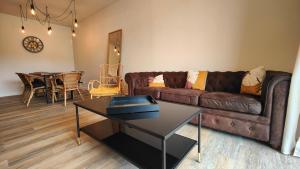 a living room with a brown couch and a table at Apartamento com terraços privativos em resort de luxo in Alvor