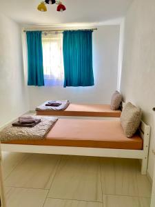 1 dormitorio con 2 camas y cortinas azules en CONFORT HOUSE, en Lugoj