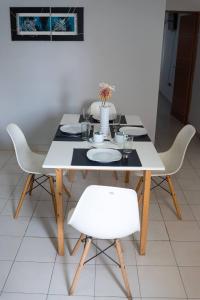 een tafel met witte stoelen en een witte tafel met borden bij Departamentos Marilian in Salta