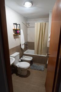 een badkamer met een toilet, een wastafel en een bad bij Departamentos Marilian in Salta