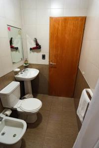 een badkamer met een toilet, een wastafel en een houten deur bij Departamentos Marilian in Salta